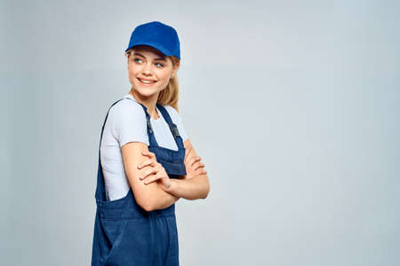 woman in work uniform blue cap service delivery service light backgroundの写真素材