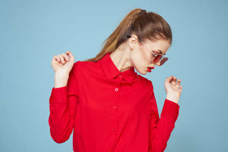 Woman with dark glasses red lips charm shirt studio blue backgroundの写真素材