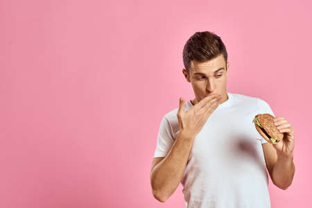 man with big hamburger on pink background calories fast food cropped view Copy Space close-upの写真素材