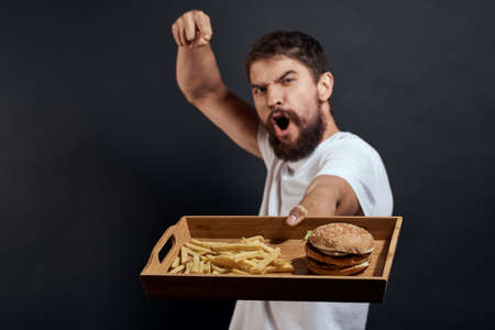 Woman man with pallet of fast food fries and hamburger diet food restaurant white t-shirt dark backgroundの写真素材