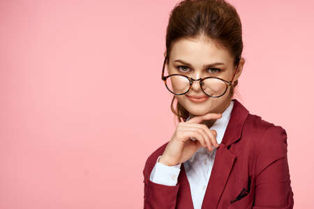 Business woman red jacket glasses executive lifestyle studio pink backgroundの写真素材