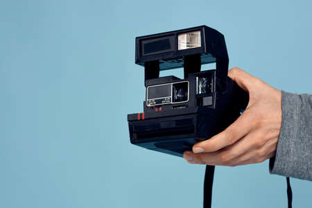 Photo camera in the hands of a man professional shooting lens technology studio equipment blue background. High quality photoの写真素材