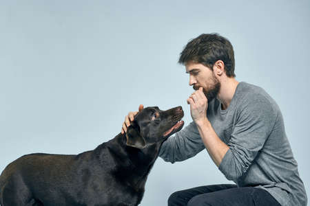 The man trains the dog indoors and gestures with his hands to execute the models commandsの写真素材