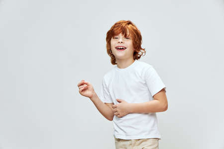 Joyful red-haired boy in a white T-shirt. Wide smile emotionsの写真素材