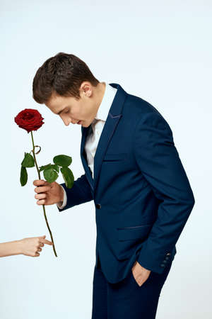 A man in a suit with a rose in his hands a gift date light backgroundの写真素材