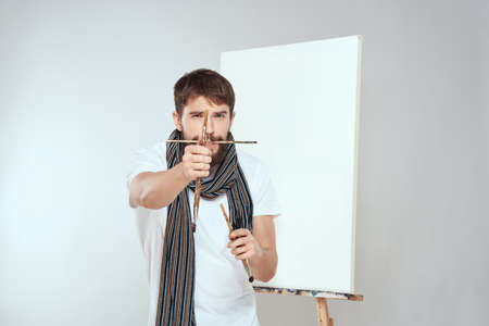 Male artist brush in hands of easel art hobby light background scarf around his neckの写真素材