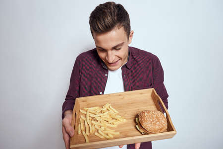 Man eating wooden pallet fast food french fries hamburger diet food restaurant light backgroundの写真素材