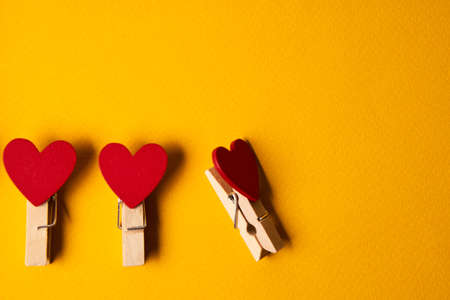 Red clothespins in the form of hearts on a yellow background close-up number of itemsの写真素材