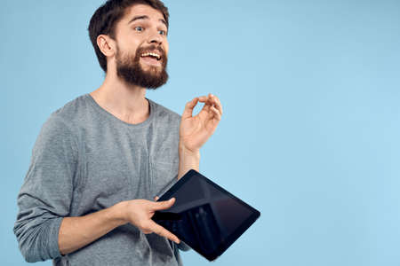 Man holding tablet in hands wireless technology internet lifestyle studio blue background emotionsの写真素材
