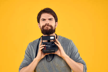 Male photographer with professional photo camera. Professional Creative approach studio yellow backgroundの写真素材