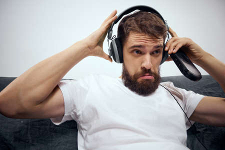 A man sits on a sofa with a gamepad in his hand. Leisure lifestyle game console