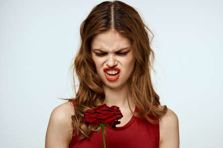 Beautiful woman in a red dress holds a rose in her hand a gift flowers decoration attractive look