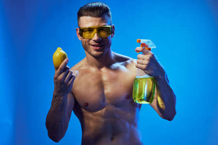 A man with a pumped-up naked torso lemon in the hands of a detergent cleaningの写真素材