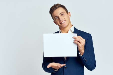A business man in a suit holds a paper in the hand of an official manager light background