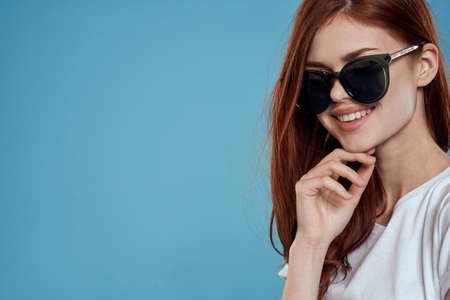 Pretty woman in sunglasses charm long hair white t-shirt blue backgroundの写真素材