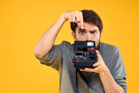 Male photographer with professional photo camera. Professional Creative approach studio yellow backgroundの写真素材