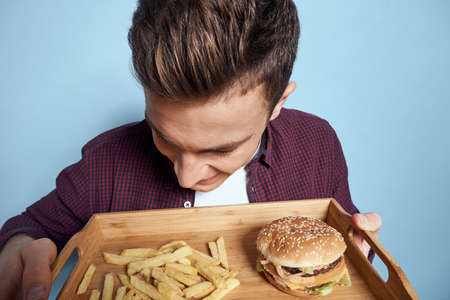 Man with wooden pallet fast food french fries hamburger hunger diet food blue background