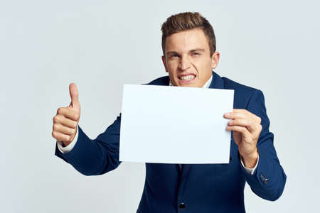 A business man in a suit holds a paper in the hand of an official manager light background