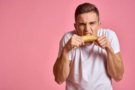 Man with fruits in hands on a pink background healthy food vitamins pink background white t-shirt modelの写真素材