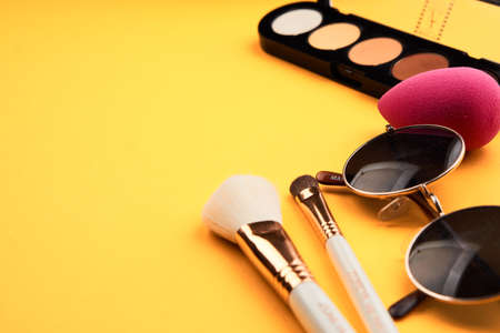 Eyeshadows on a yellow background professional cosmetics makeup brushes soft sponge fashion glasses