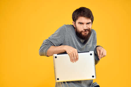 man with laptop wireless technology internet lifestyle work yellow isolated backgroundの写真素材