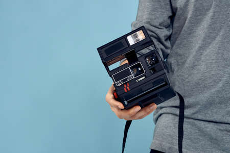 Photo camera in the hands of a man professional shooting lens technology studio equipment blue...