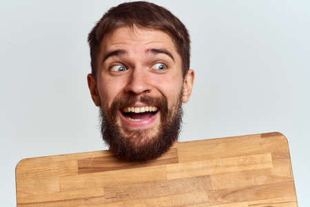 Man with a kitchen wooden board and with a shovel on a light background emotions white t-shirt modelの写真素材