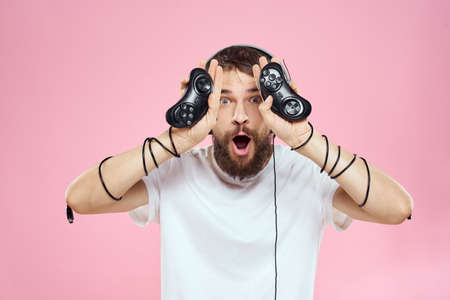 Man in headphones with joysticks in hands playing games lifestyle fun entertainment pink background