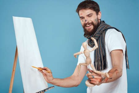 Male artist with a wooden dummy in hands drawing Creative hobby blue backgroundの写真素材