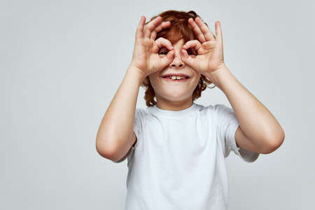 Grimacing boy holds his hands near his face and in the form of a mask smile childhoodの写真素材