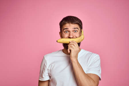 bearded man with banana in hand on pink background fun emotions modelの写真素材