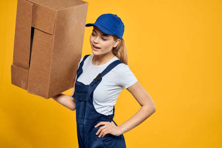 Working woman in uniform box in hands delivery courier service rendering yellow background