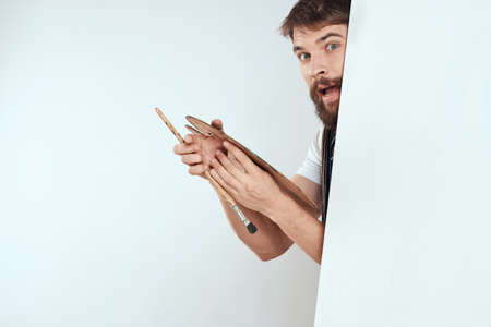 Male artist hiding behind an easel palette drawing art