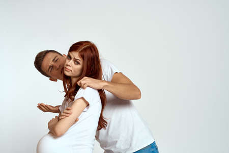 a pregnant woman and a young man are waiting for a baby on a light background emotions family loveの写真素材