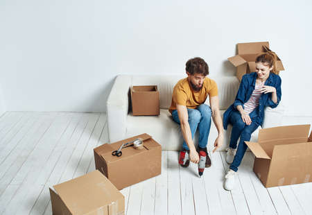 young couple on white couch with boxes of fun chatting