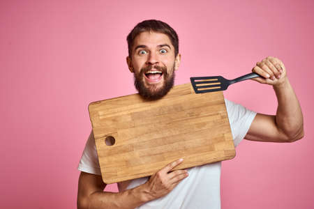 guy holding kitchen board and spatula in hand on pink background cropped viewの写真素材