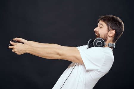 Man with joystick in hands headphones technology leisure game lifestyle dark isolated backgroundの写真素材