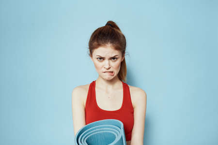 Sportive woman in red tank top mat for workout exercises lifestyle blue backgroundの写真素材