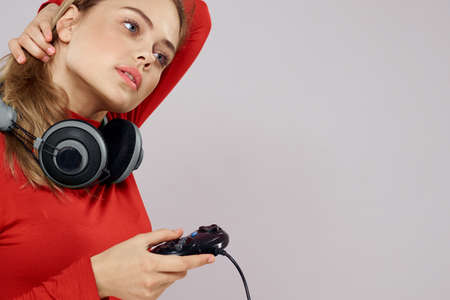 Woman with headphones controller in hands a console game fun leisure red jacket lifestyle light...
