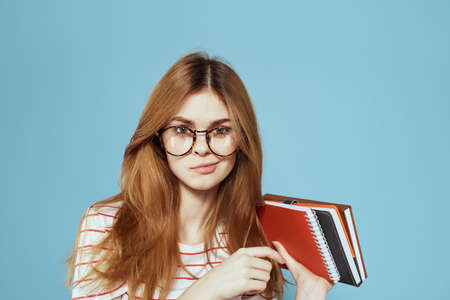 energetic female student with notepads and glasses model blue background