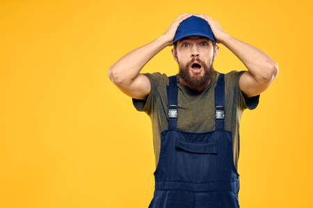 Worker man in uniform worker service yellow background emotionの写真素材