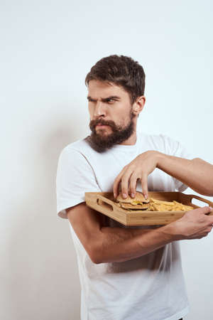 man with wooden tray fries and hamburger fast food calories model white t-shirtの写真素材