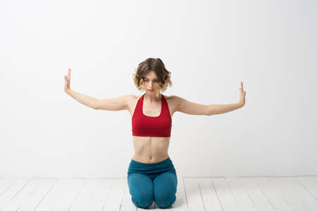 the girl is engaged in yoga on a light background Red T-shirt gesticulating with his hands