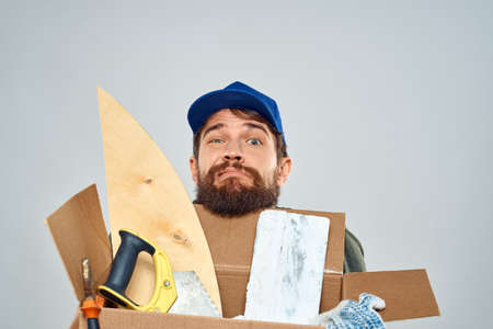 man in work uniform with box in hands tools lifestyle light background