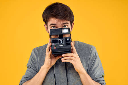 Male photographer with professional photo camera. Professional Creative approach studio yellow backgroundの写真素材