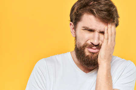 Man in white t-shirt emotions studio gestures with hands displeased facial expression yellow...