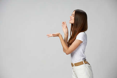 woman in a white t-shirt gestures with her hands on a light background