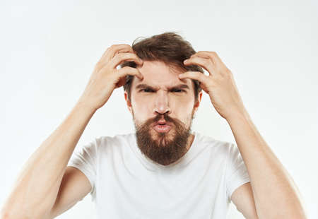A young man in a white T-shirt gestures with his hands emotions irritability stressの写真素材