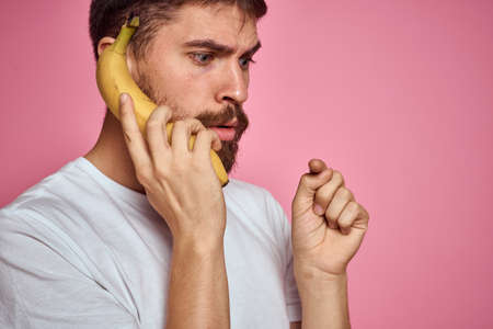 bearded man with banana in hand on pink background fun emotions modelの写真素材
