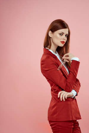 Elegant woman in red blazer glasses holding red lips pink backgroundの写真素材